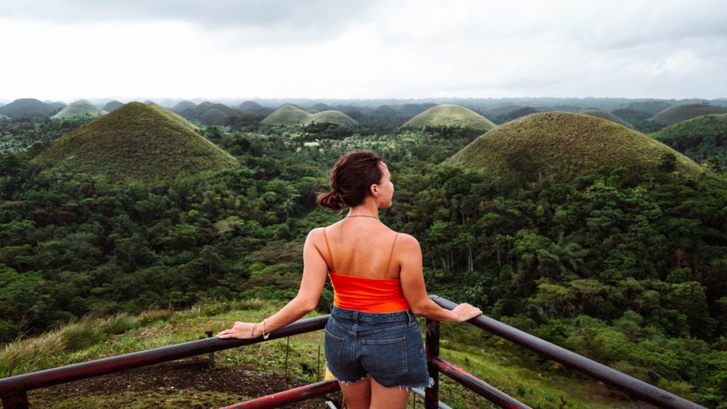 Girl standing and looking at the Chocolate Hills landscape under a clear sky