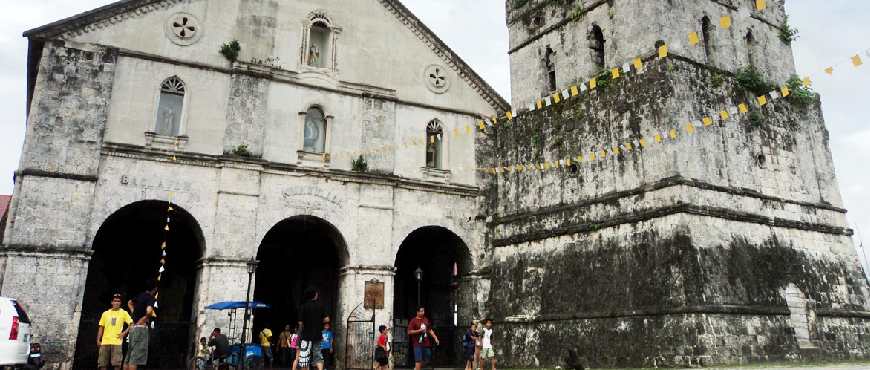 Tourist visiting Baclayon Church in Bohol, standing in front of the historic stone façade