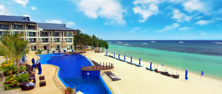 Beachfront view of The Bellevue Resort Bohol with infinity pool, white sand beach, and turquoise sea