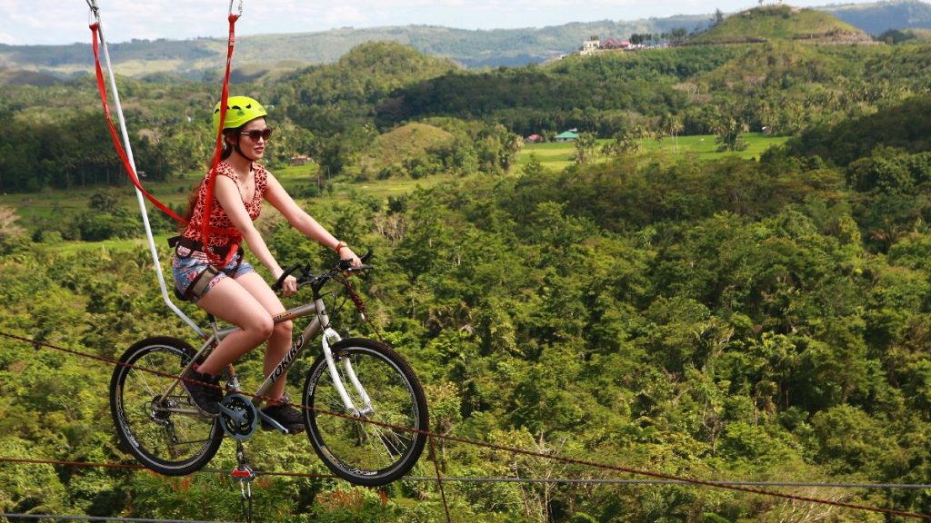 Adventure zipline experience in Bohol with a rider suspended above a forested valley